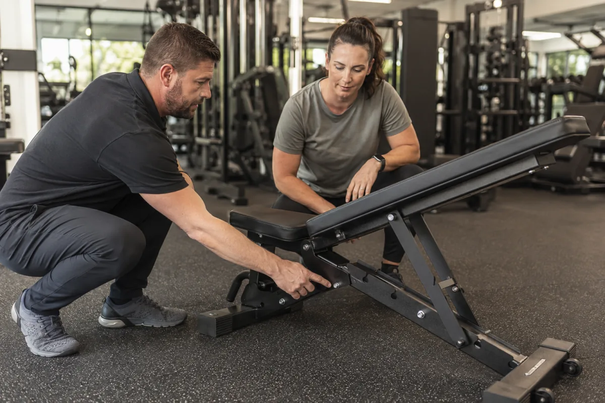 Gym owner inspecting the build quality of a commercial weight bench